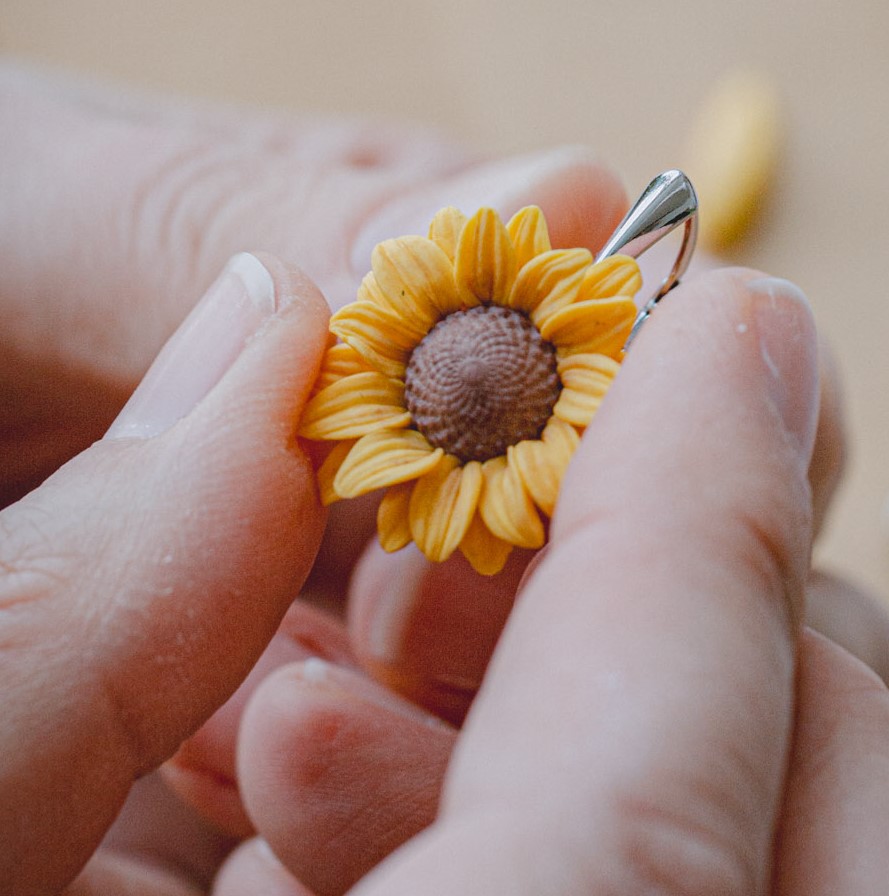 Hands finishing a polymer clay sunflower