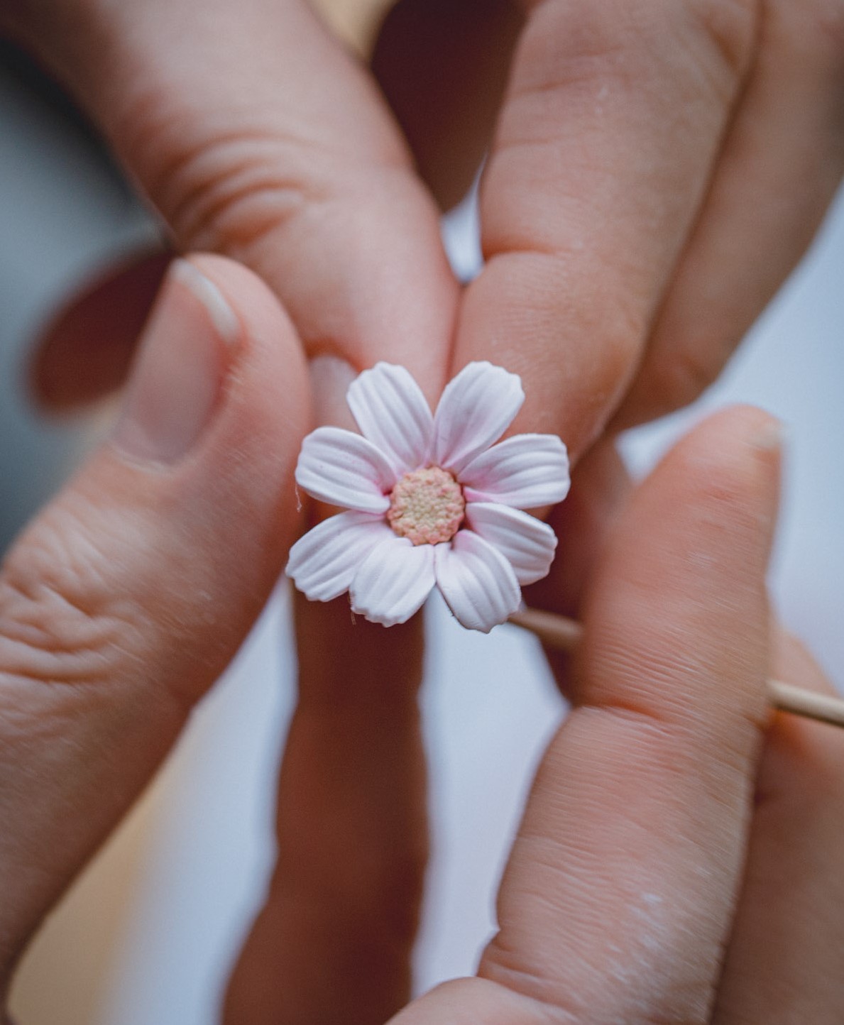 White polymer clay daisy held in hand